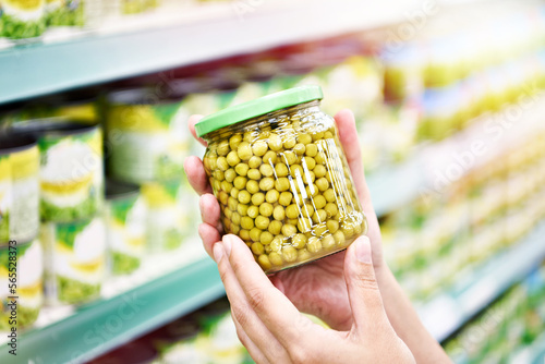 Green peas in jar in hands at shop