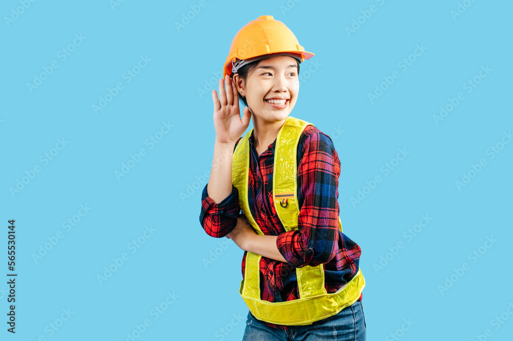 Young female engineer hand over ear to making hear gesture