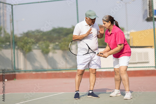 Tennis instructor teaches senior woman to hold the racket correctly.