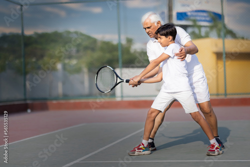 Grandfather showing his cute grandson tennis ball before playing  © G-images