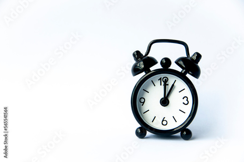 Black alarm clock pointing at 1 o'clock with customizable space for text on white background. Copy space and time concept.