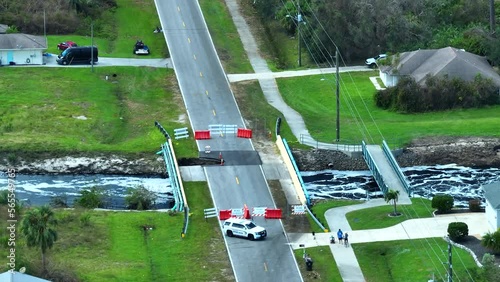 Aerial view of police patroling damaged road bridge over river after flood water washed away asphalt. Rebuilding of ruined transportation infrastructure photo