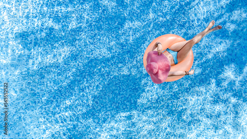 Beautiful woman in hat in swimming pool aerial top view from above, young girl in bikini relaxes and swims on inflatable ring donut and has fun in water on tropical vacation on holiday resort 