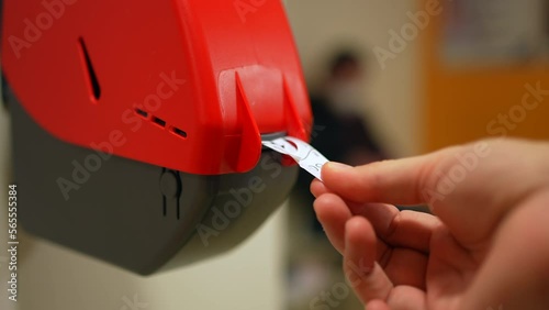 Closeup of Waiting Number Machine. Customer hand pulls a numbered ticket in dispenser machine. wait in service line photo