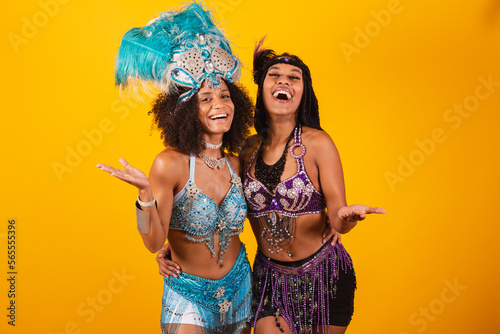 two Brazilian women friends, in carnival clothes. inviting hands. photo