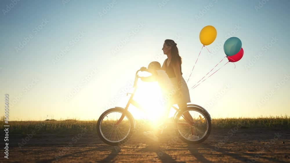 mom teaches son to ride a bike. happy family childhood dream concept. mom and little son learn to ride sunlight a bike silhouette in the park in nature. happy family goes in for sports outdoors