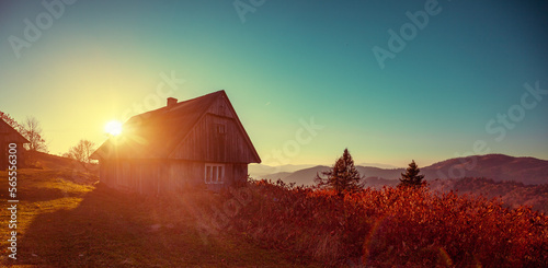 Silhouette of wooden hut in the early morning. View of the mountains in autumn. Carpathian mountains. Ukraine Horizontal banner