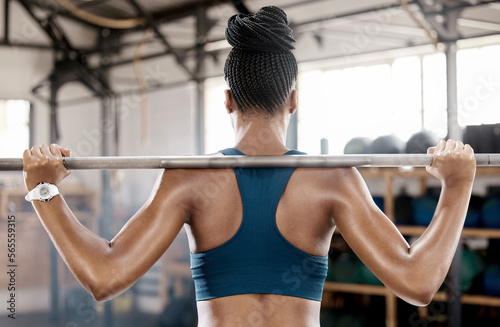 Fitness, black woman or bodybuilder with a barbell in training, workout or exercise for body goals. Back view, mindset or sports athlete weightlifting with strong biceps or focus at gym club studio