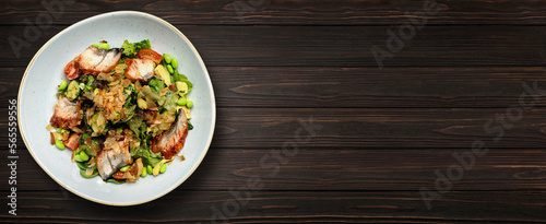 Salad with grilled eel and vegetables on a plate, on a wooden background
