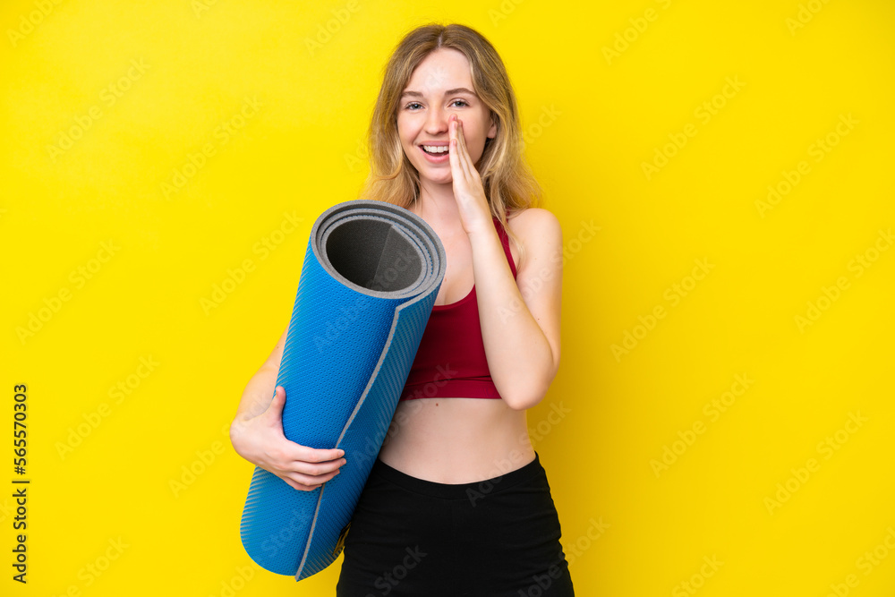 Young sport caucasian woman going to yoga classes while holding a mat isolated on yellow background shouting with mouth wide open Young sport caucasian woman going to yoga classes while holding a mat isolated on yellow background shouting with mouth wide open