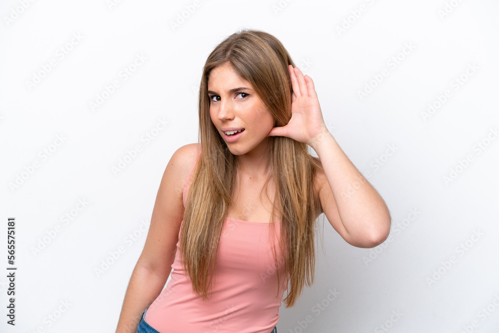 Young caucasian woman isolated on white bakcground listening to something by putting hand on the ear