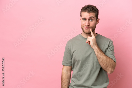 Young caucasian man isolated on pink background and thinking