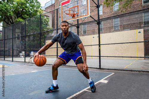 Athletic african american basketball player training on a court in New York - Sportive man playing basket outdoors © oneinchpunch