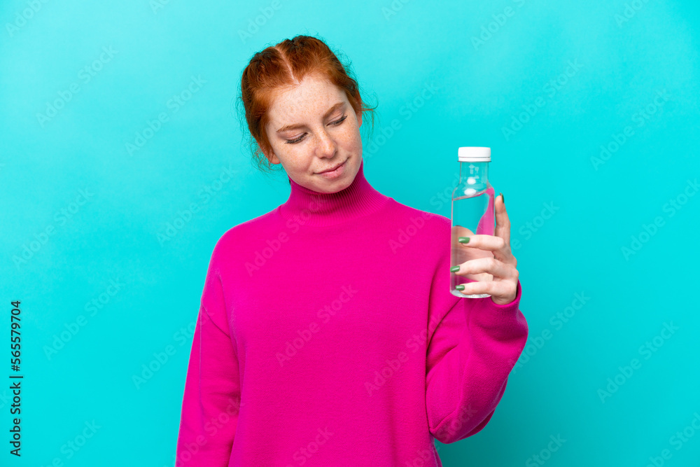 Young caucasian reddish woman with a bottle of water isolated on blue background with sad expression Young caucasian reddish woman with a bottle of water isolated on blue background with sad expression