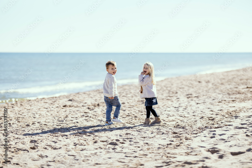 Two toddlers on the beach smiling with mutual understanding