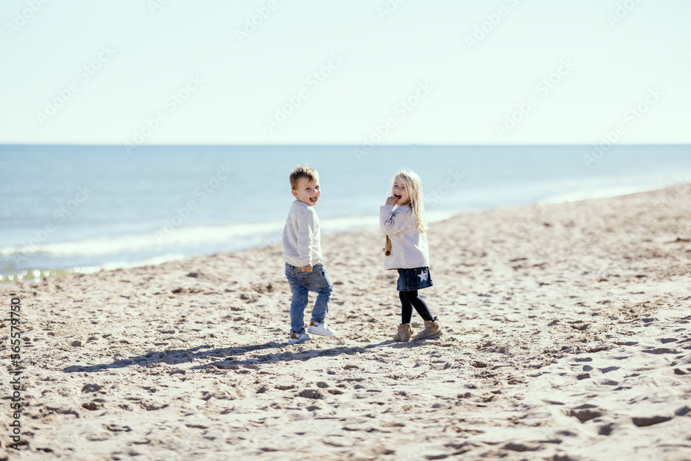 Two toddlers on the beach smiling with mutual understanding