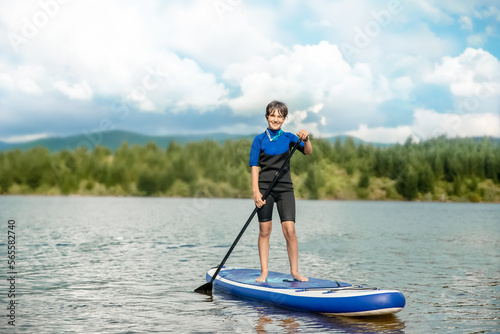 active teen girl paddling a sup board on a river or lake, natural background, active healthy sporty lifestyle