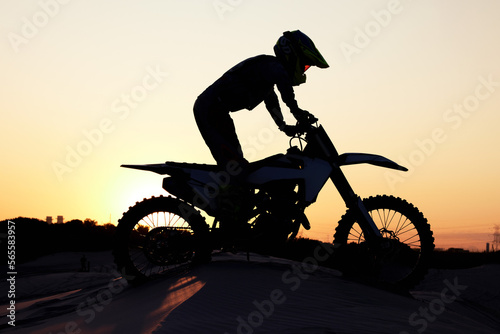 Silhouette, sports and motorcycle riding against sunset, sky and background in nature, extreme sport and adrenaline. Biking, motorbike and person driving on dirt road, sunrise and shadow or freedom