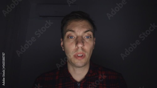 A young man communicates via video communication. Late in the evening, he fell asleep in front of the laptop screen. Colleagues wake him up, the man wakes up, answers questions, nods. His face tired.