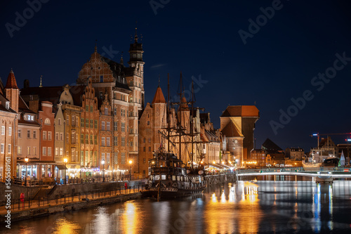 Night image of the river and the buildings of the city of Gdansk (Poland) illuminated, capturing the reflection of the water with a medieval ship.