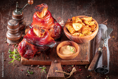 Canvas Print Hot roasted pork knuckle on a plate with baked potatoes.