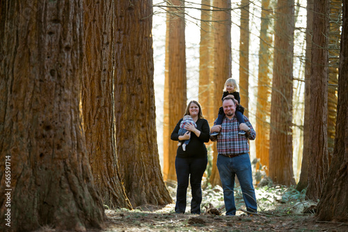Family of four smiling in a forest setting