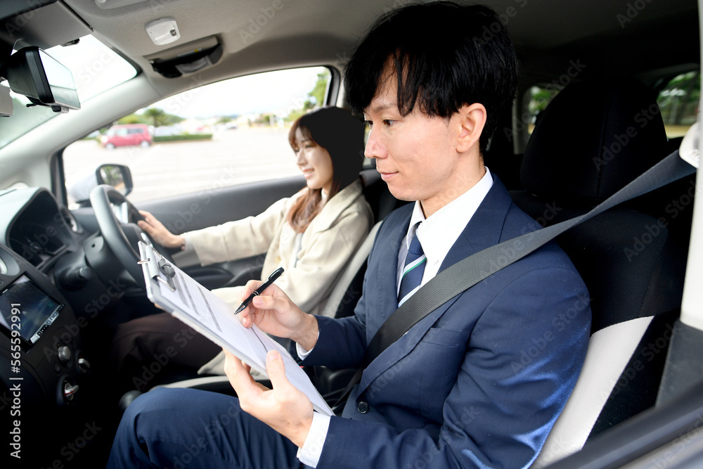 車の運転教習をする男性教官と女性生徒 車の運転教習をする男性教官と女性生徒