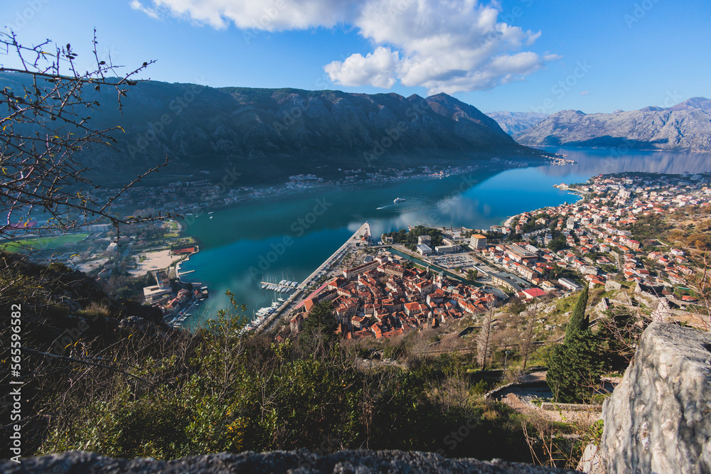 Obraz premium Kotor, Montenegro, process of climbing to the top of San Giovanni Fortress, Fort St. John, old medieval town, hiking on the Ladder of Kotor, sunny day with a blue sky and mount Lovcen and Orjen