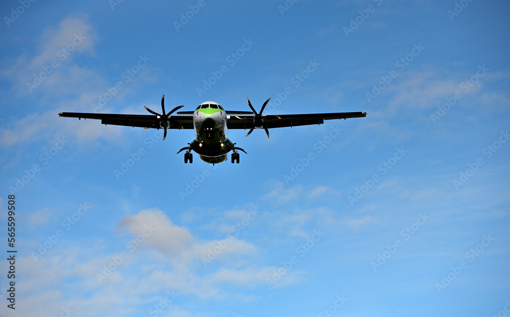Fototapeta premium Ein Propellerflugzeug ist im Landeanflug bei blauem Himmel und vereinzelten Wolken