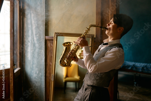 Foto Young elegant man playing gold alto saxophone in misty room