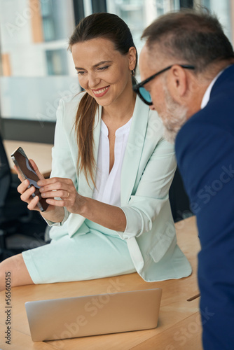 Excited female entrepreneur showing smartphone screen to colleague