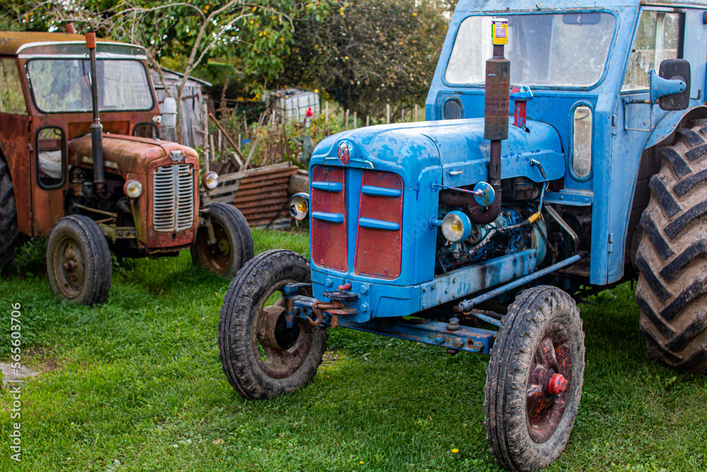 Obraz premium Two old rusty tractors in a backyard.