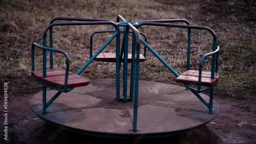 A carousel without people turns lonely on the playground. The atmosphere of desolation