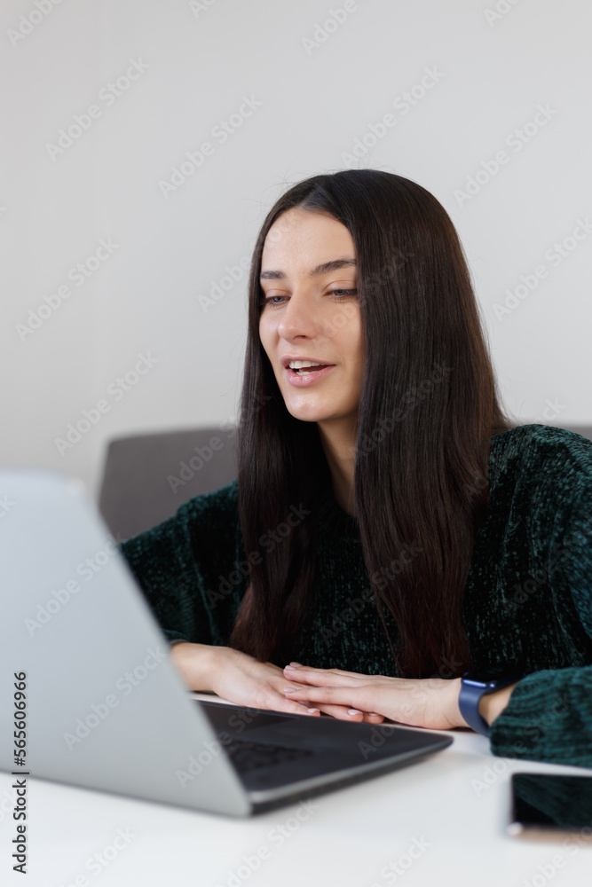 Young entrepreneur talks on web camera during video call. White female person in late 20s speaking on laptop web cam at home Young entrepreneur talks on web camera during video call. White female person in late 20s speaking on laptop web cam at home