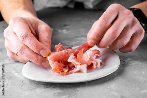 man chef hand takes Prosciutto crudo, parma ham photo