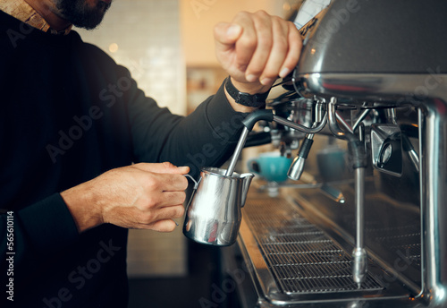 Hands, man and barista brewing at coffee shop using machine for hot beverage, caffeine or steam. Hand of employee male steaming milk in metal jug for premium grade drink or self service at cafe