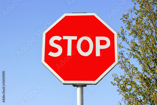 Bright red and white Stop traffic sign against the blue sky.