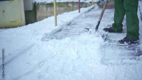A manual worker clears snow from a sidewalk alley in a residential area in the city.