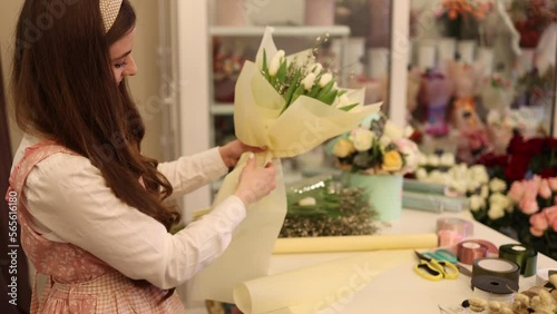 Flowers delivery shop. Florist creating order, making spring bouquet. Female make bouquet using tulips
