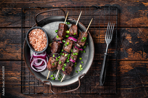 Kebabs grilled meat skewers, shish kebab with onion and herbs, grilled beef meat. Wooden background. Top view