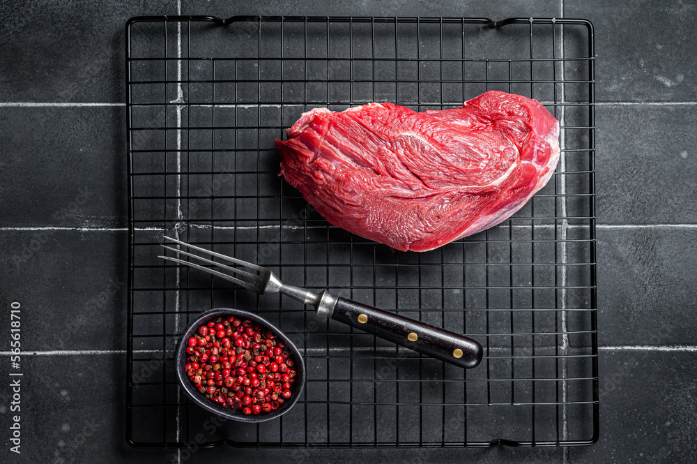 Raw beef meat piece for grilling with spices. Black background. Top view