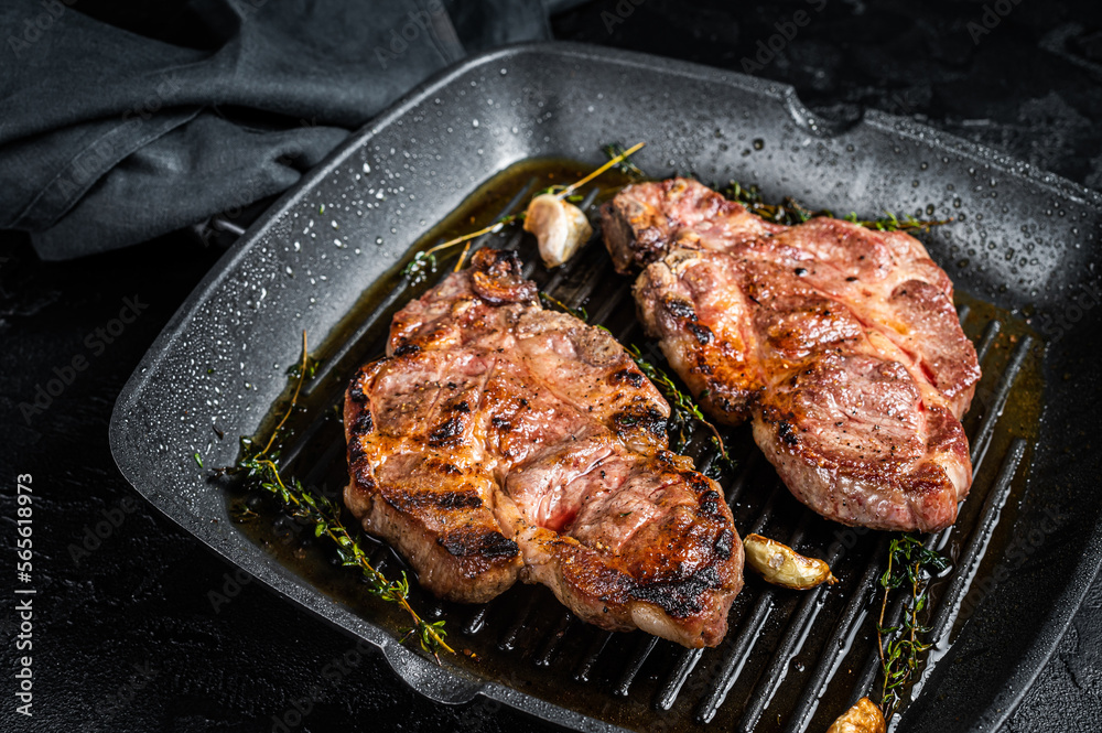 Grilled Pork steaks, neck meat on grill pan. Black background. Top view