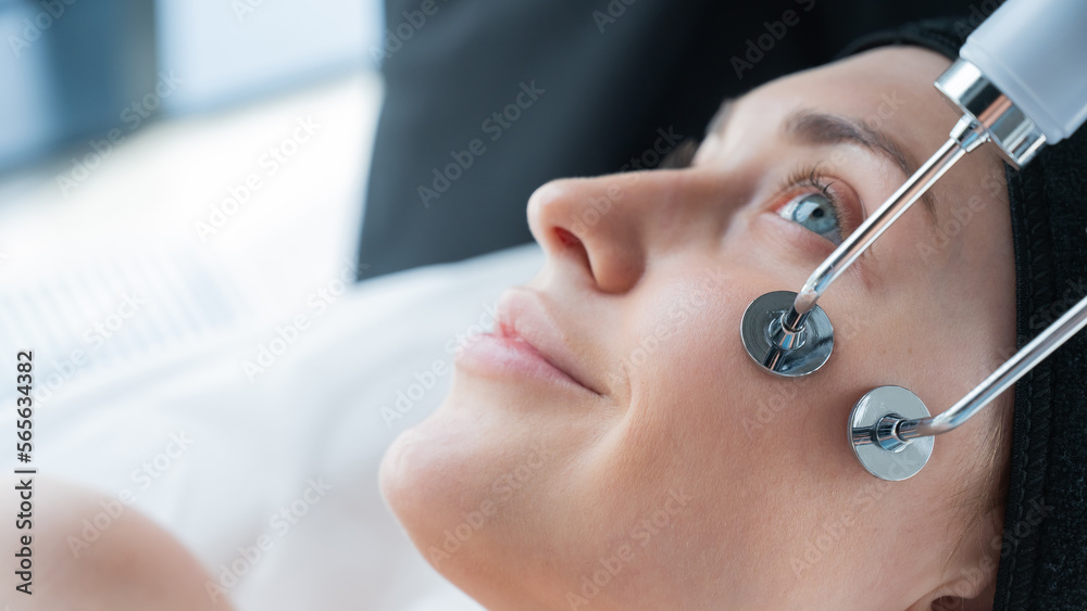 Naklejka premium Young caucasian woman on microcurrent therapy procedure. Beautician's office.
