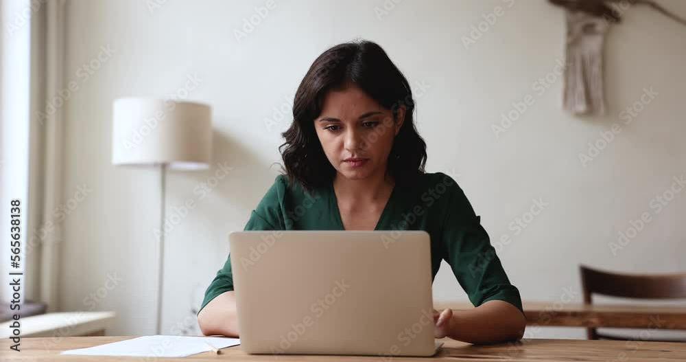 Serious pretty Asian business woman working at laptop in small co-working office, sitting at workplace table, thinking on project idea, typing on computer, using online app for job communication Serious pretty Asian business woman working at laptop in small co-working office, sitting at workplace table, thinking on project idea, typing on computer, using online app for job communication