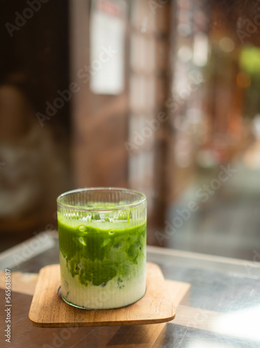 Image of a mug of matcha green tea mix milk on a brown wooden coaster.