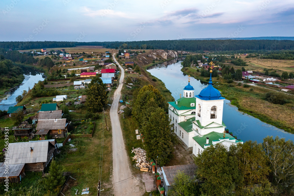 View of a Russian village with a spilled river and a beautiful old Orthodox church on shore a birds eye view from a drone