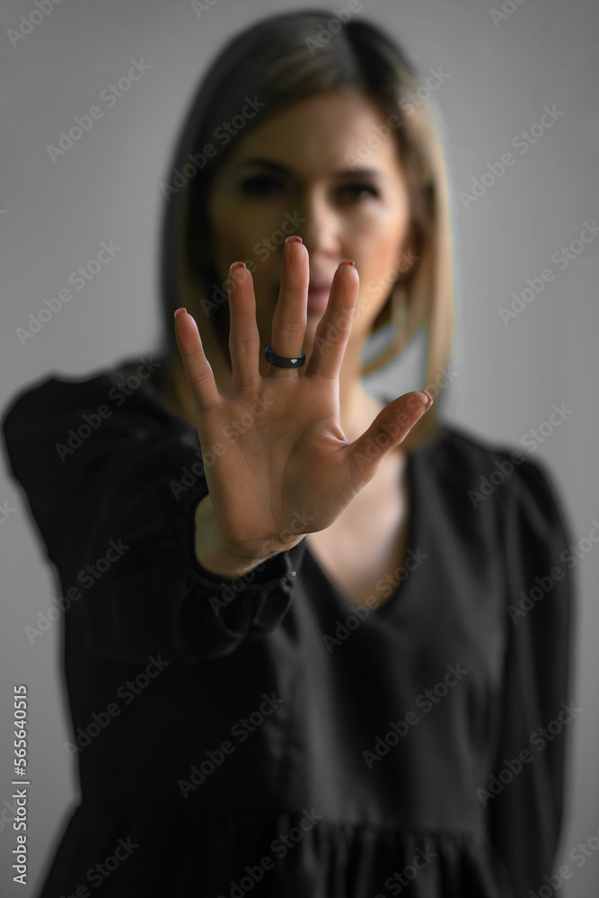 Φωτογραφία Girl, young woman in dark clothes shows palm, hand forward, stop sign and no