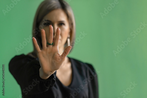 Girl, young woman in dark clothes shows palm, hand forward, stop sign and no. Hand signs, the ability to say no. selective focus