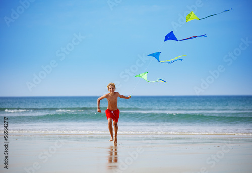 Boy run on the beach holding a colorful kite group