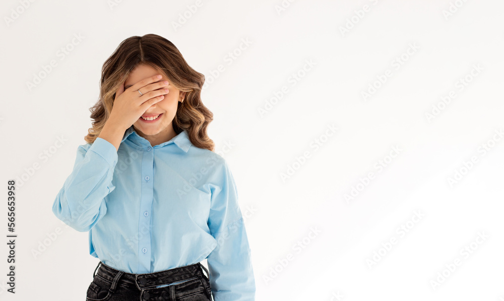 Cheerful pretty young European female making facepalm, holding hand on forehead, did something stupid and smiling. Human emotions, expression concept. Awkwardness gestures. Epic fail emotion